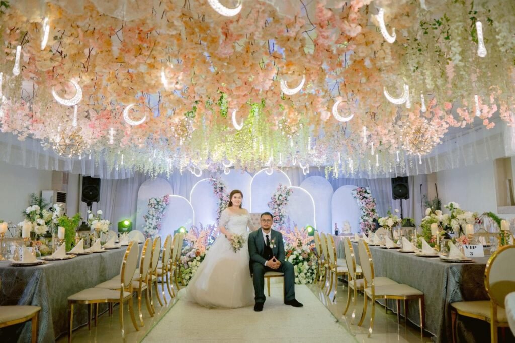 Romantic wedding setup in Davao City with a bride and groom under a luxurious floral ceiling, chandeliers, and elegant reception styling by a wedding planner and event organizer.
