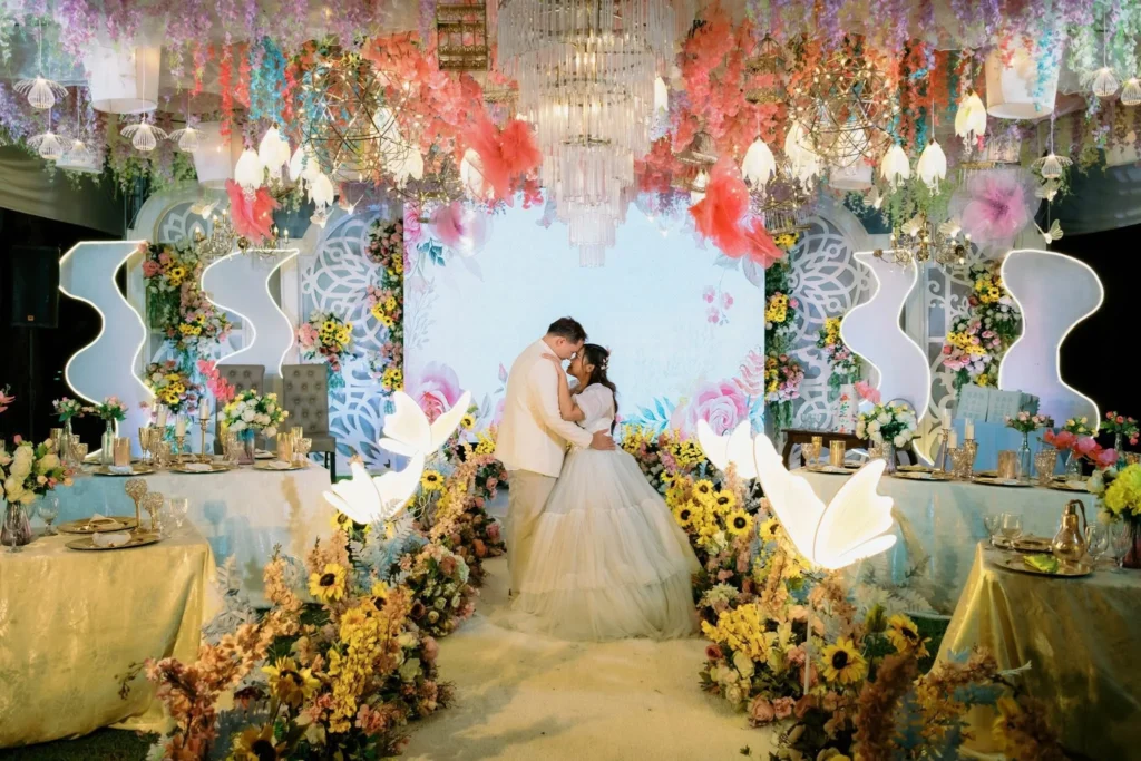 Romantic wedding setup in Davao City with a bride and groom under a luxurious floral ceiling, chandeliers, and elegant reception styling by a wedding planner and event organizer.